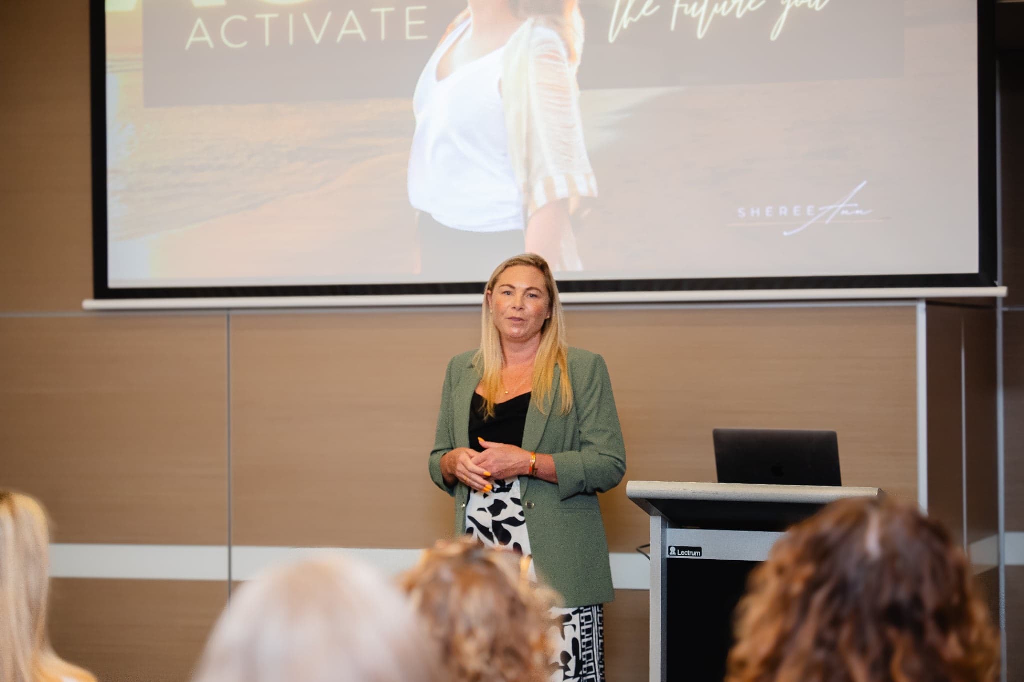 Sheree Ann speaking on stage at a RECALIBRATE event, activate the future you